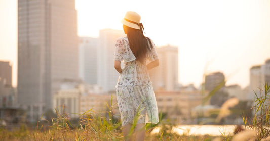 Femme en robe d'été portant un chapeau dans une prairie ensoleillée