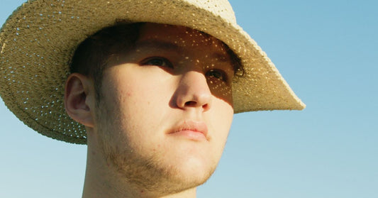 Homme portant un chapeau de paille sous un ciel bleu d'été